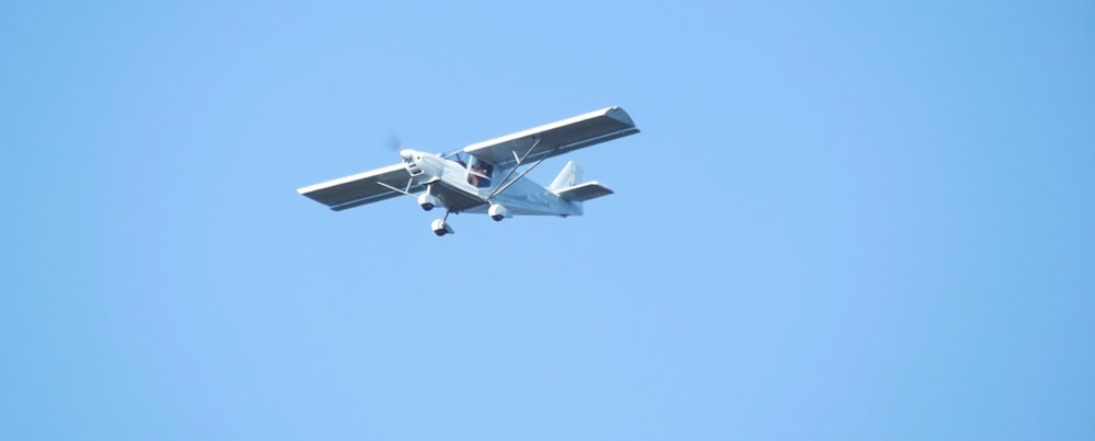 a small airplane flying through a blue sky