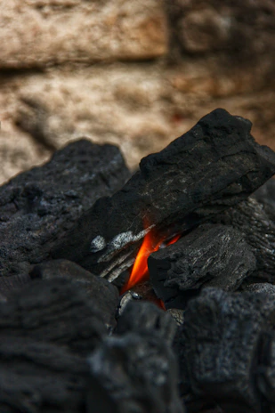 Artistic shot of glowing charcoal pieces arranged on a sleek black surface.