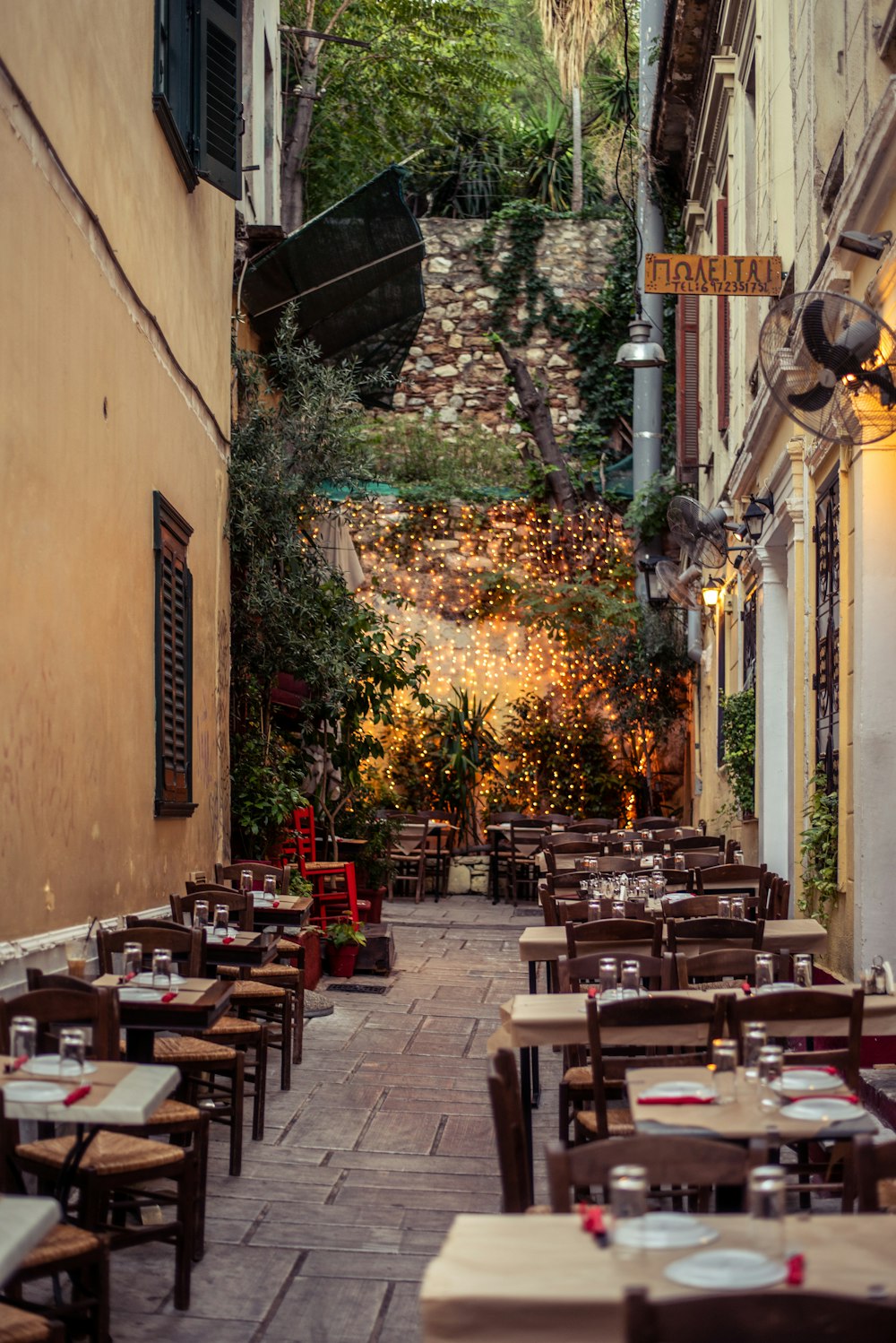 a narrow alley way with tables and chairs