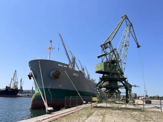 a large boat sitting in a harbor next to a crane