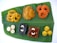 A variety of colorful Indian sweets are arranged neatly on a large green banana leaf. The sweets include swirling yellow and orange jalebis, round yellow laddoos, dark square pieces with cashew nuts, and white round shapes resembling peda or sandesh. The arrangement on the banana leaf highlights the traditional presentation style.