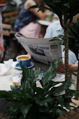A person reading a newspaper with business headlines in a cozy café.