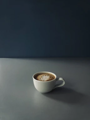 Close-up photo of a flat white coffee in a minimalist setting on light beige textured paper