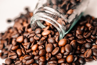 Close-up of green coffee capsules spilling from a glass jar with fresh green coffee beans around.