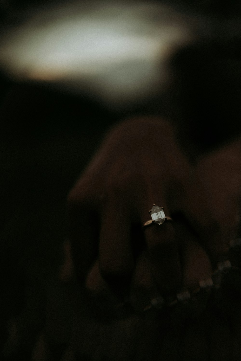 a close up of a person's hand holding a diamond ring