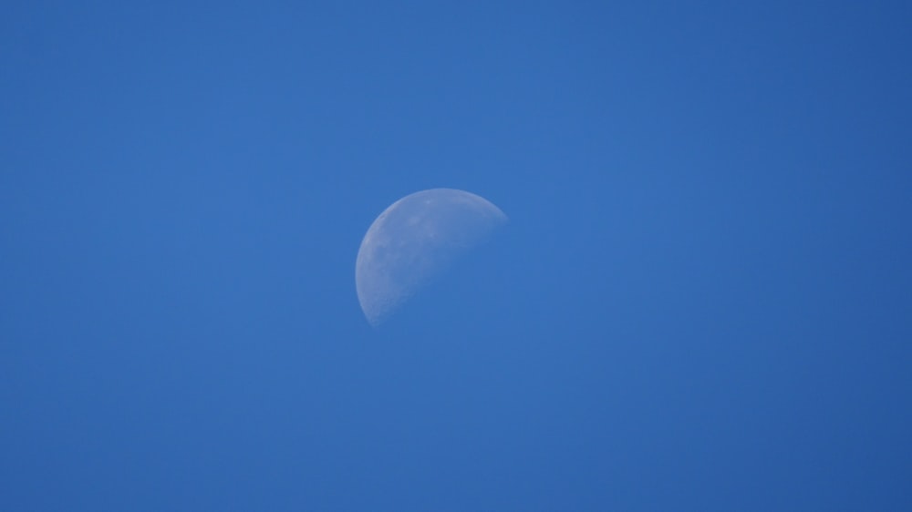 a half moon in a clear blue sky