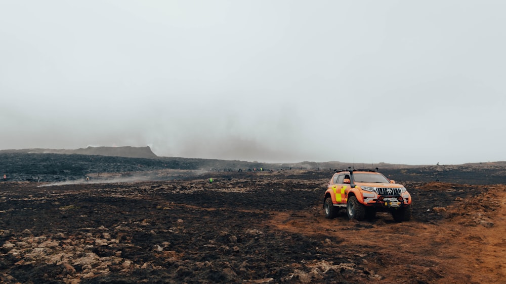 a yellow truck driving down a dirt road