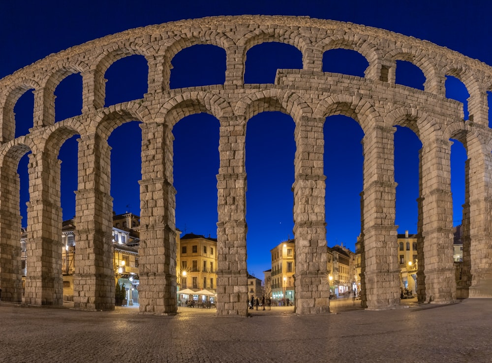 a large stone structure with arches in the middle of a street