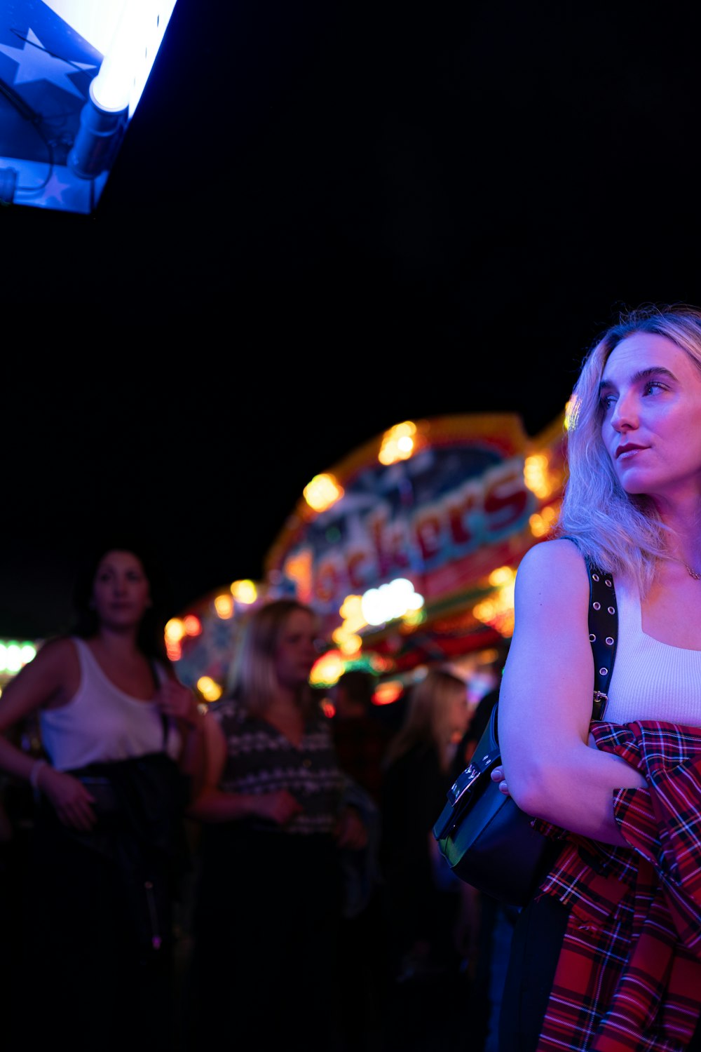 Una mujer parada frente a un carnaval por la noche