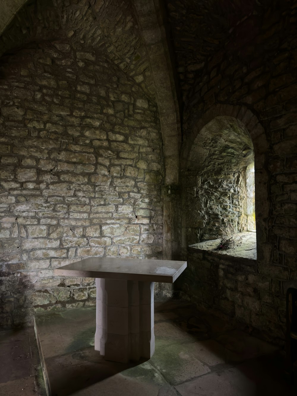 a table sitting in a stone tunnel next to a window