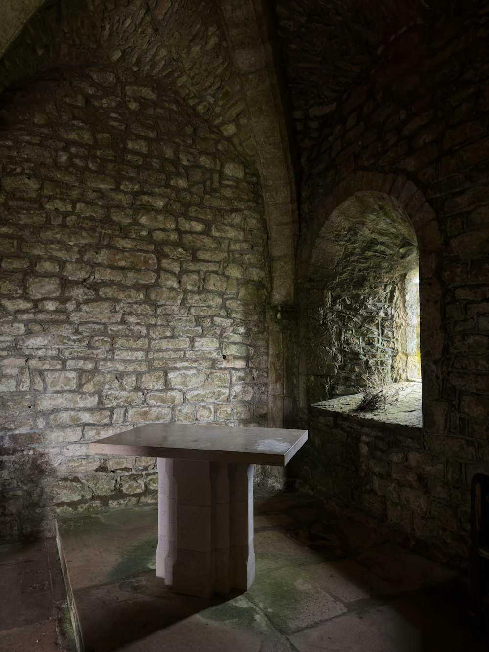 Una mesa sentada en un túnel de piedra junto a una ventana