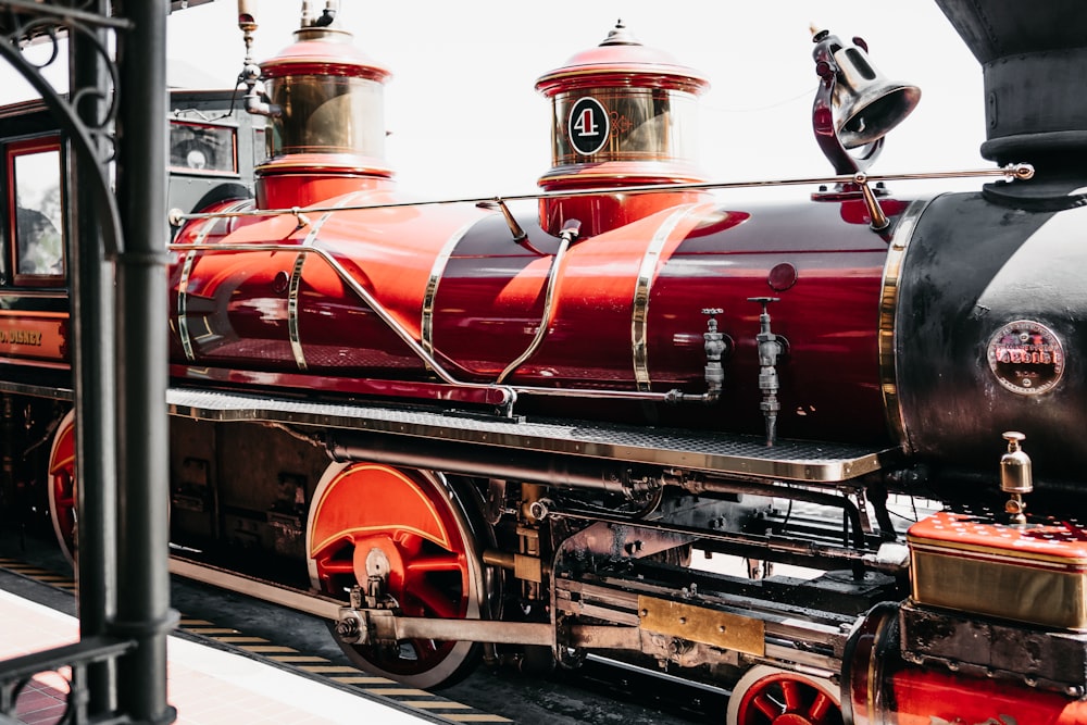 um motor de trem vermelho e preto sentado nos trilhos