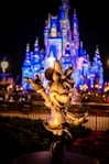 a statue of mickey mouse in front of a castle