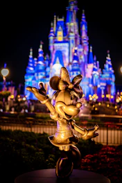 a statue of mickey mouse in front of a castle