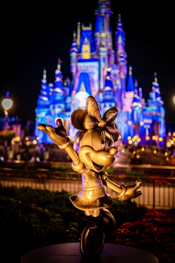 a statue of mickey mouse in front of a castle