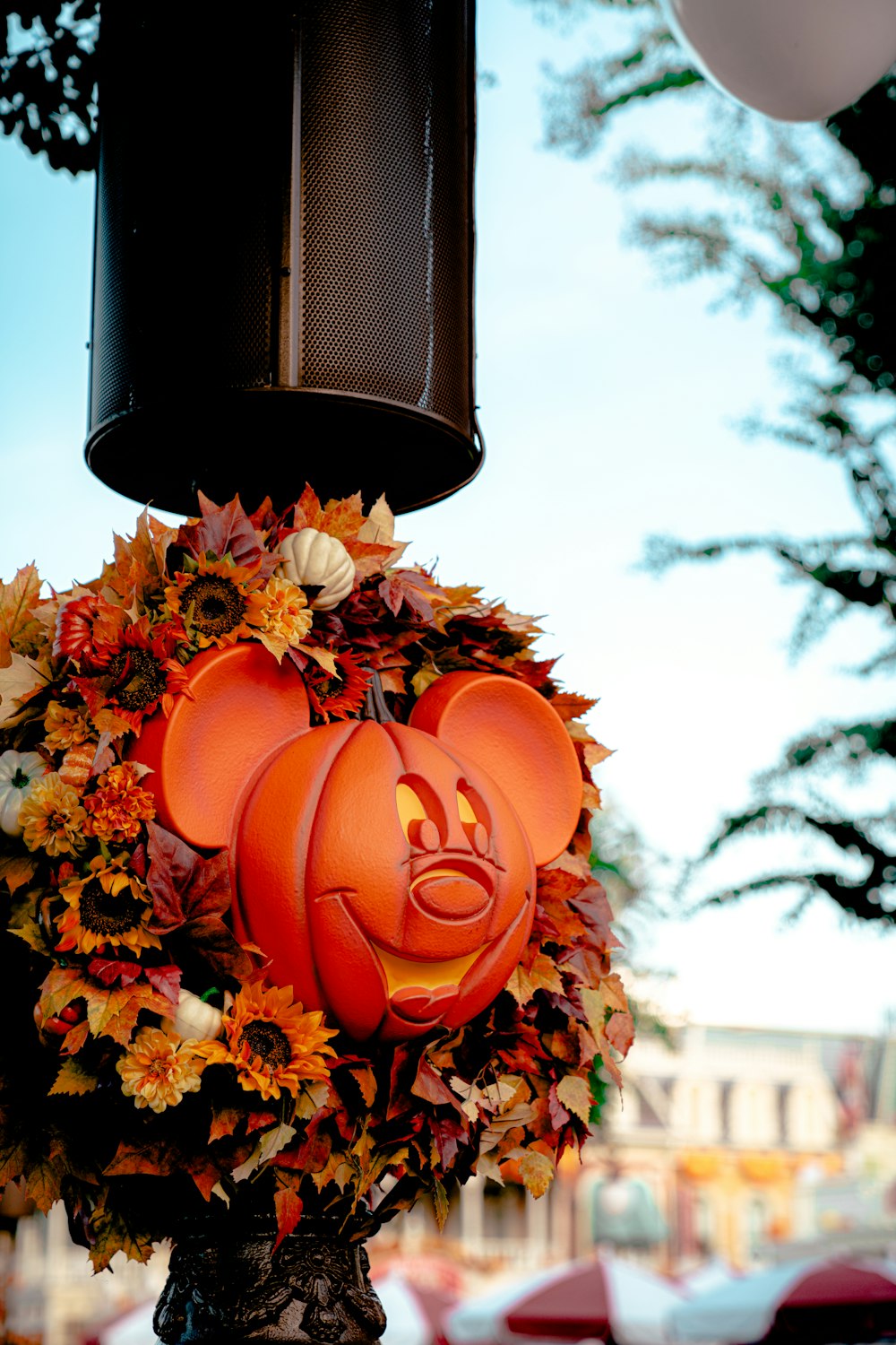 a mickey mouse pumpkin wreath hanging from a lamp post