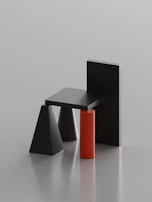 Minimalist composition of a sculptural object in matte black against a beige backdrop.
