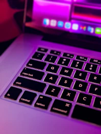Close-up of a computer technician repairing a laptop with pink-themed website interface in the background