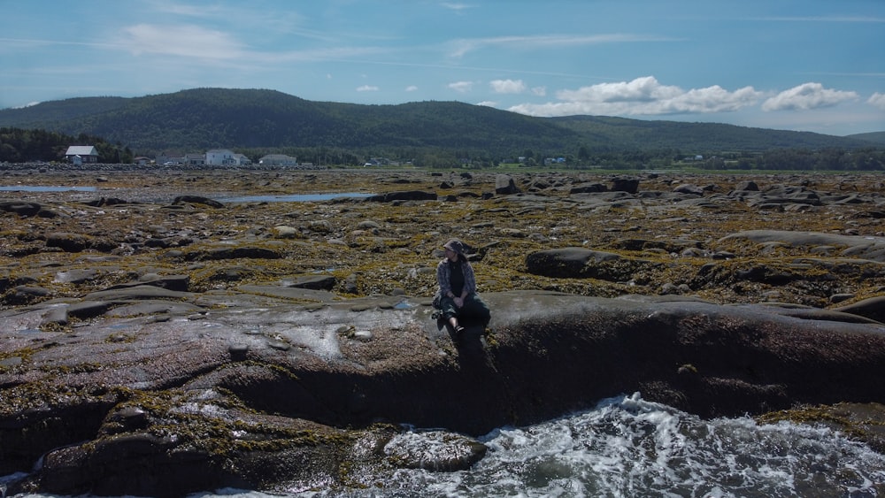 um homem em cima de uma praia coberta de rochas