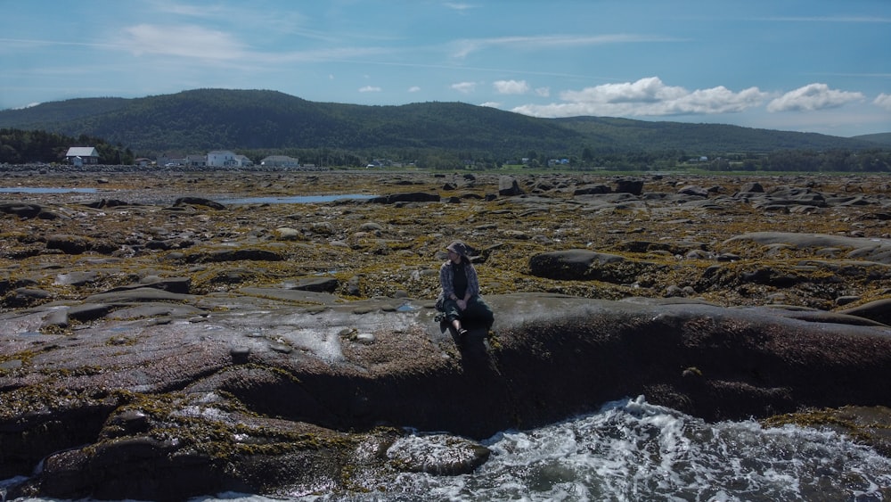 a man standing on top of a rock covered beach