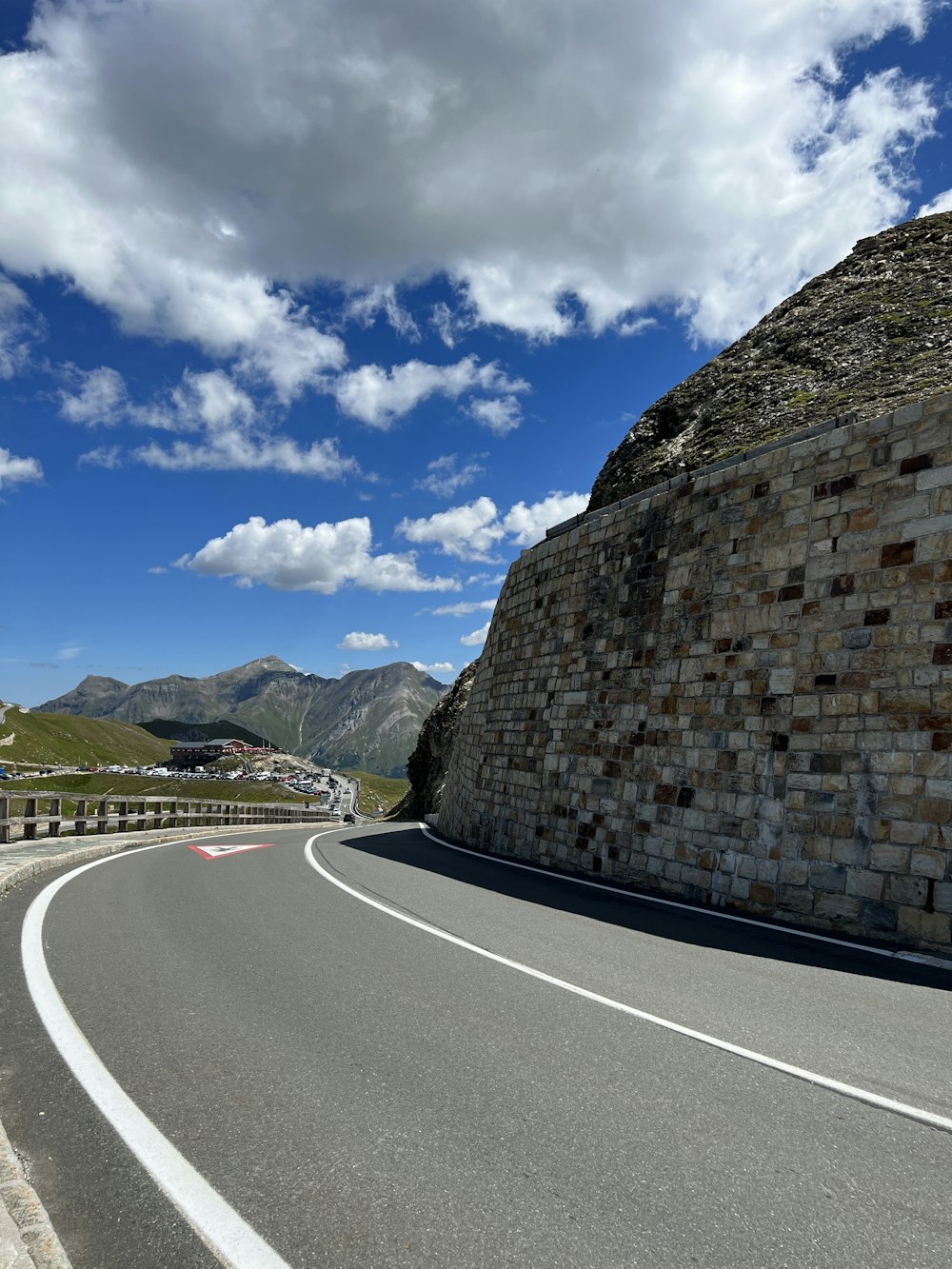 a curved road with a stone wall on the side