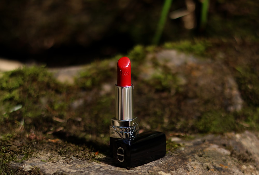 a red lipstick sitting on top of a rock