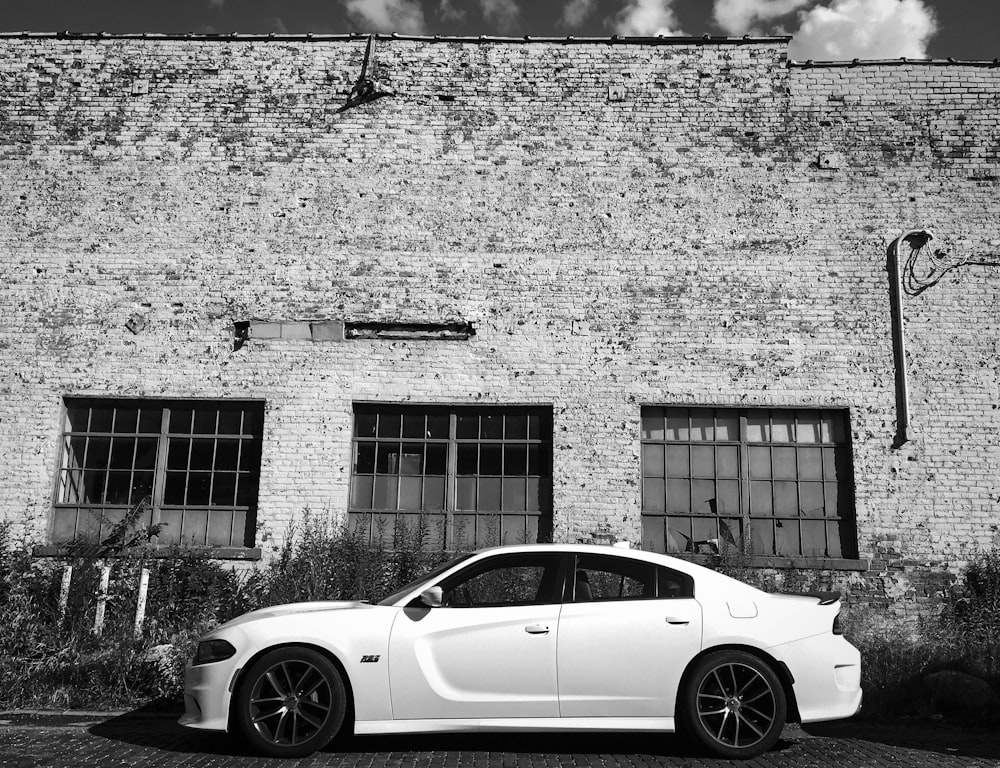 a white car parked in front of a brick building