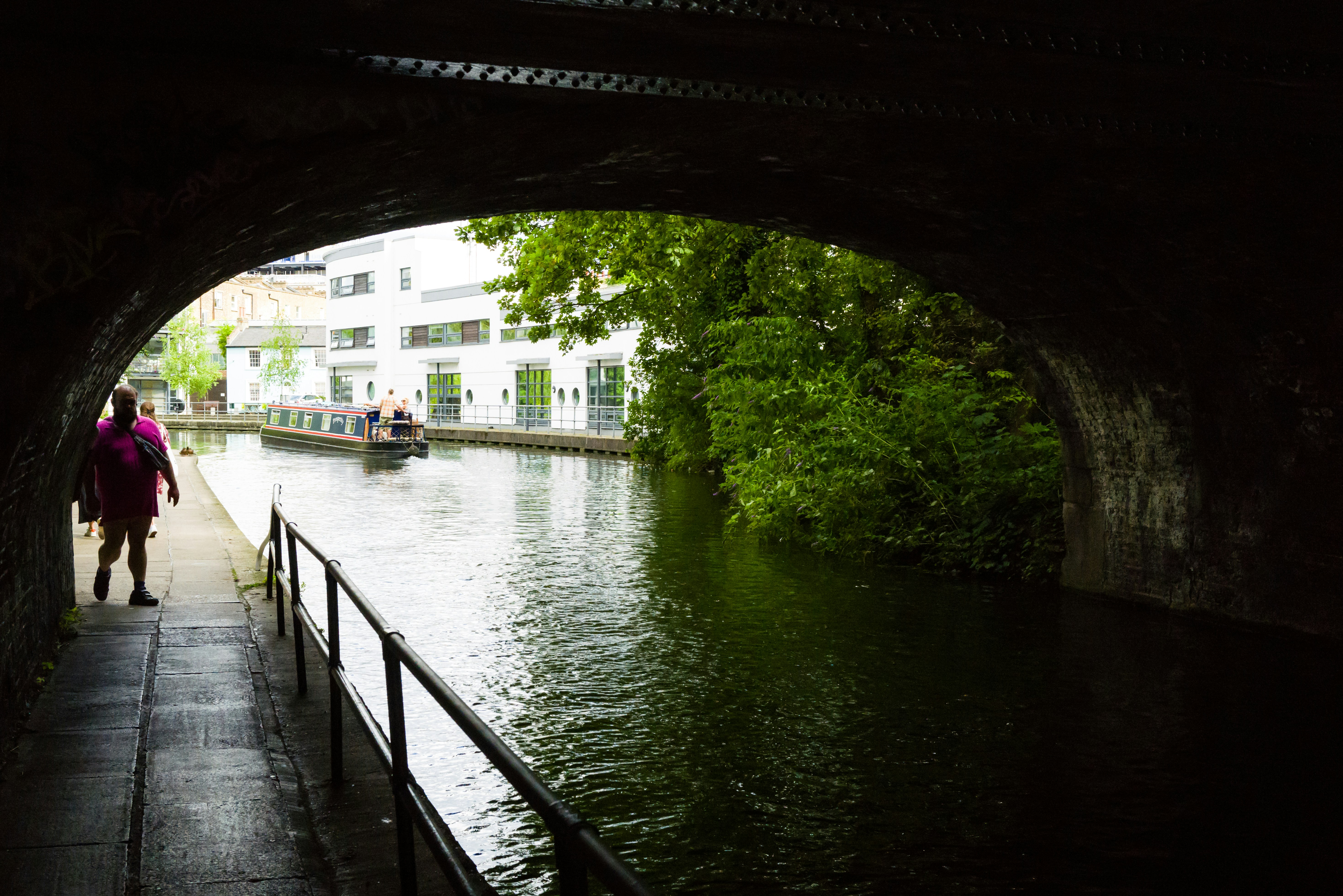a woman walking down a sidewalk next to a river