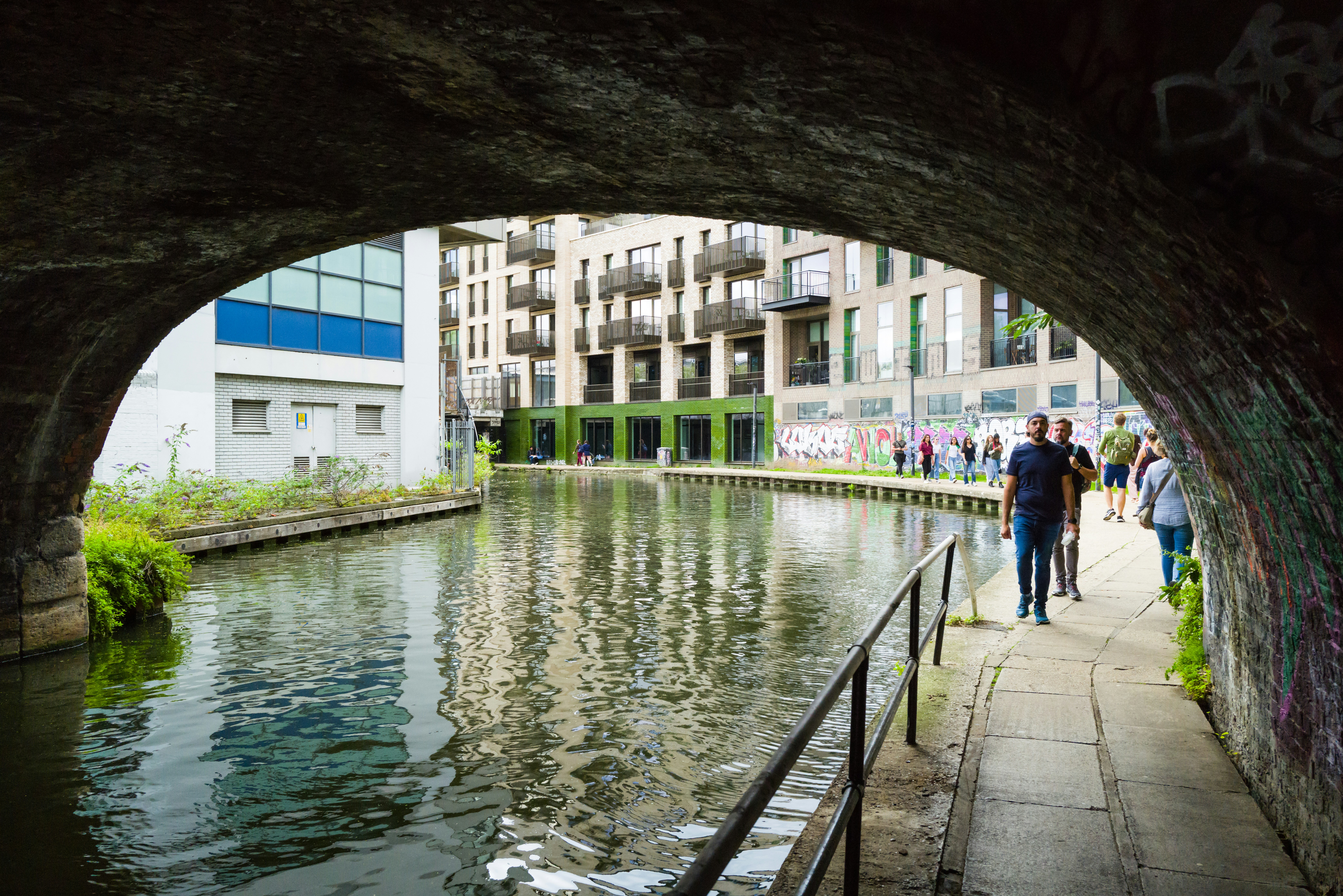 a group of people walking under a bridge over a river