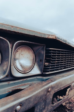A close-up of a rusty scrap car in a junkyard.