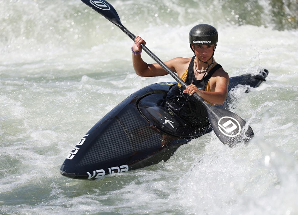 a man riding a kayak on top of a river