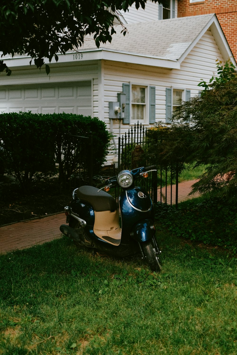 a scooter parked on the grass in front of a house