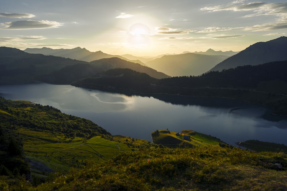 the sun is setting over a lake in the mountains