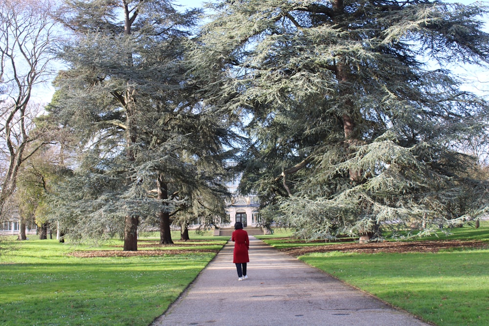 a woman in a red coat is walking down a path