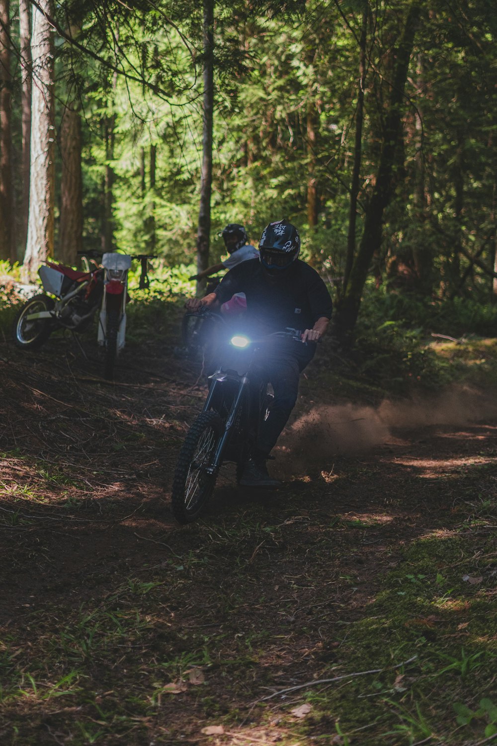 a man riding a dirt bike through a forest