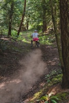 A rider cruising through a forest trail on a dirt bike.