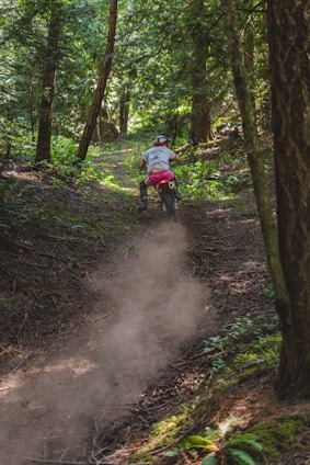 A rugged big trail motorcycle navigating a dirt trail surrounded by trees.