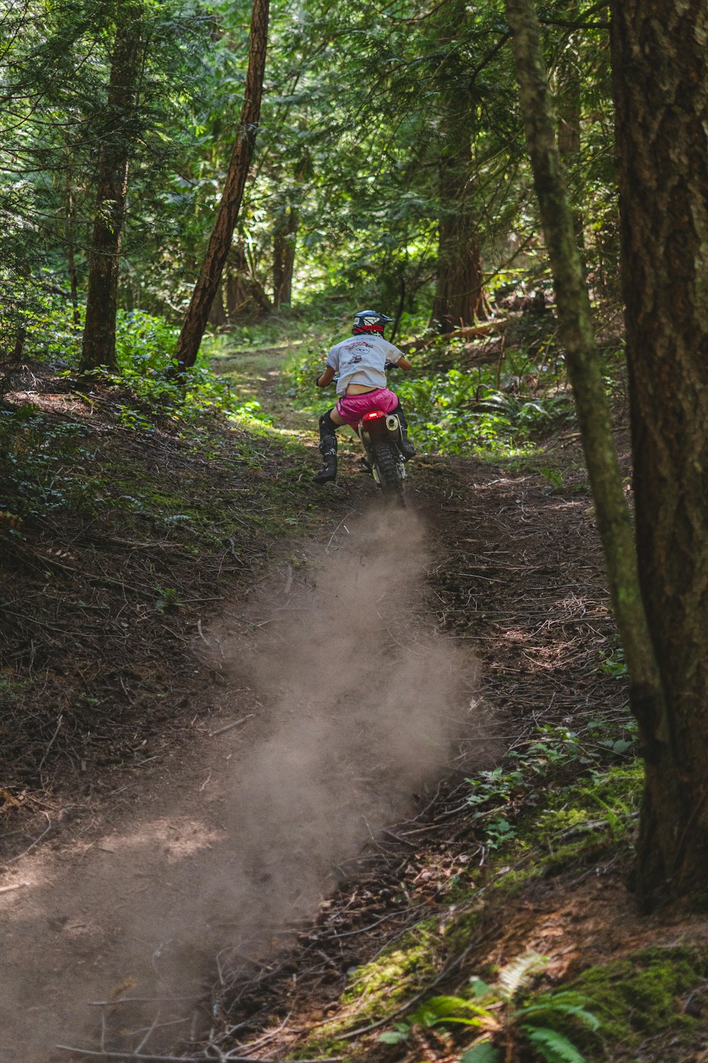 a person riding a dirt bike on a trail in the woods