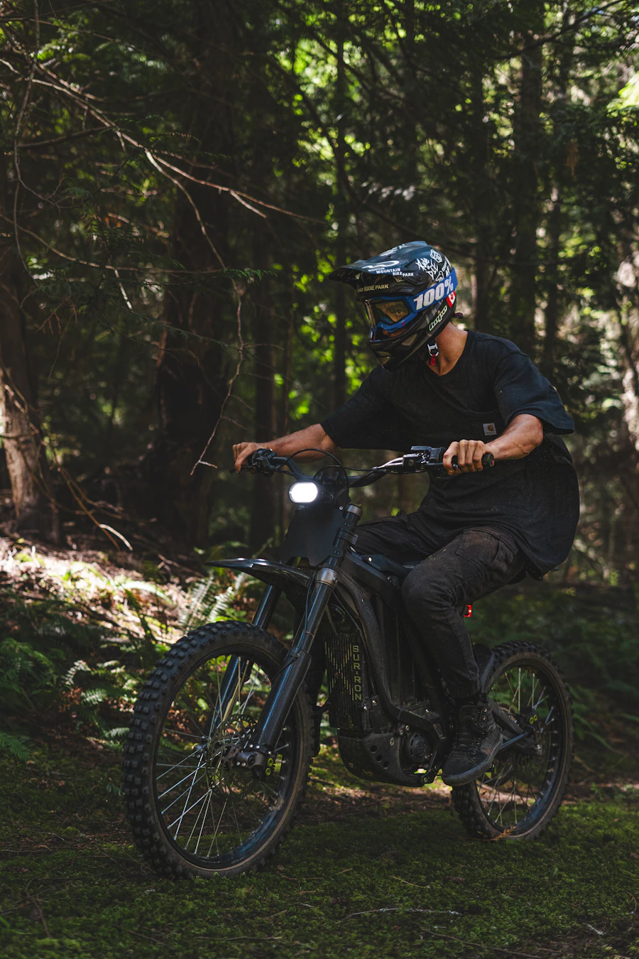 Rider on a Sur-Ron electric dirt bike on a forest trail