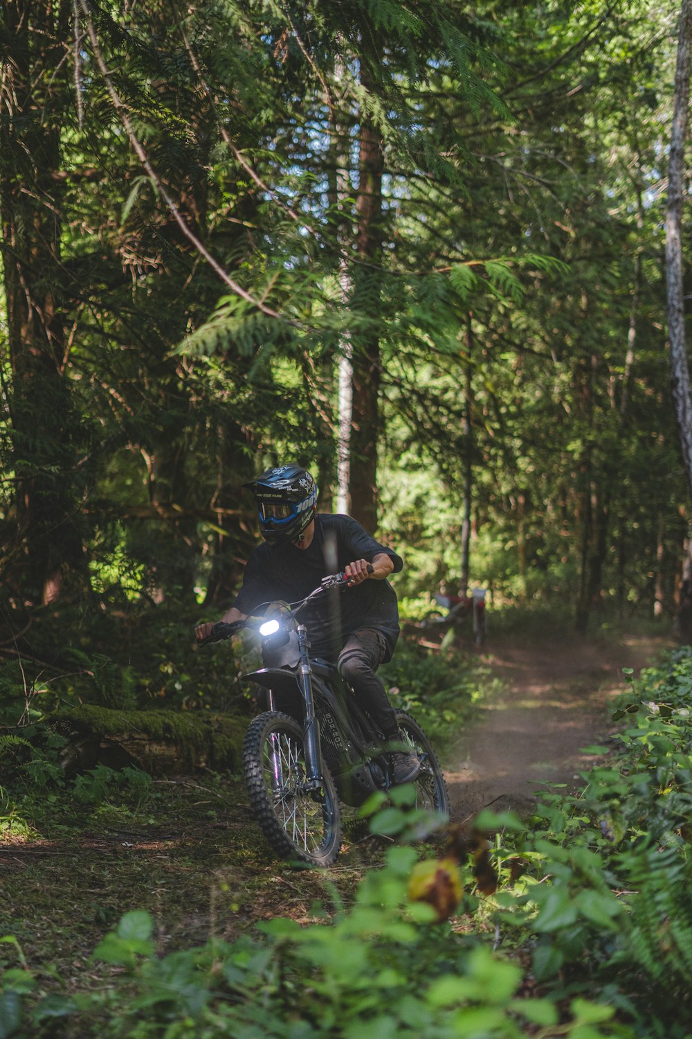 a man riding a dirt bike through a forest