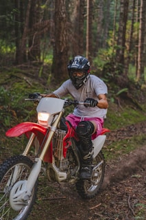 A rider navigating a dirt bike through a lush green forest trail in Bali.