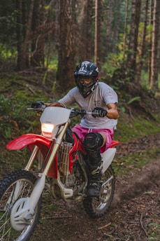 A rider navigating a dirt bike through a lush green forest trail in Bali.