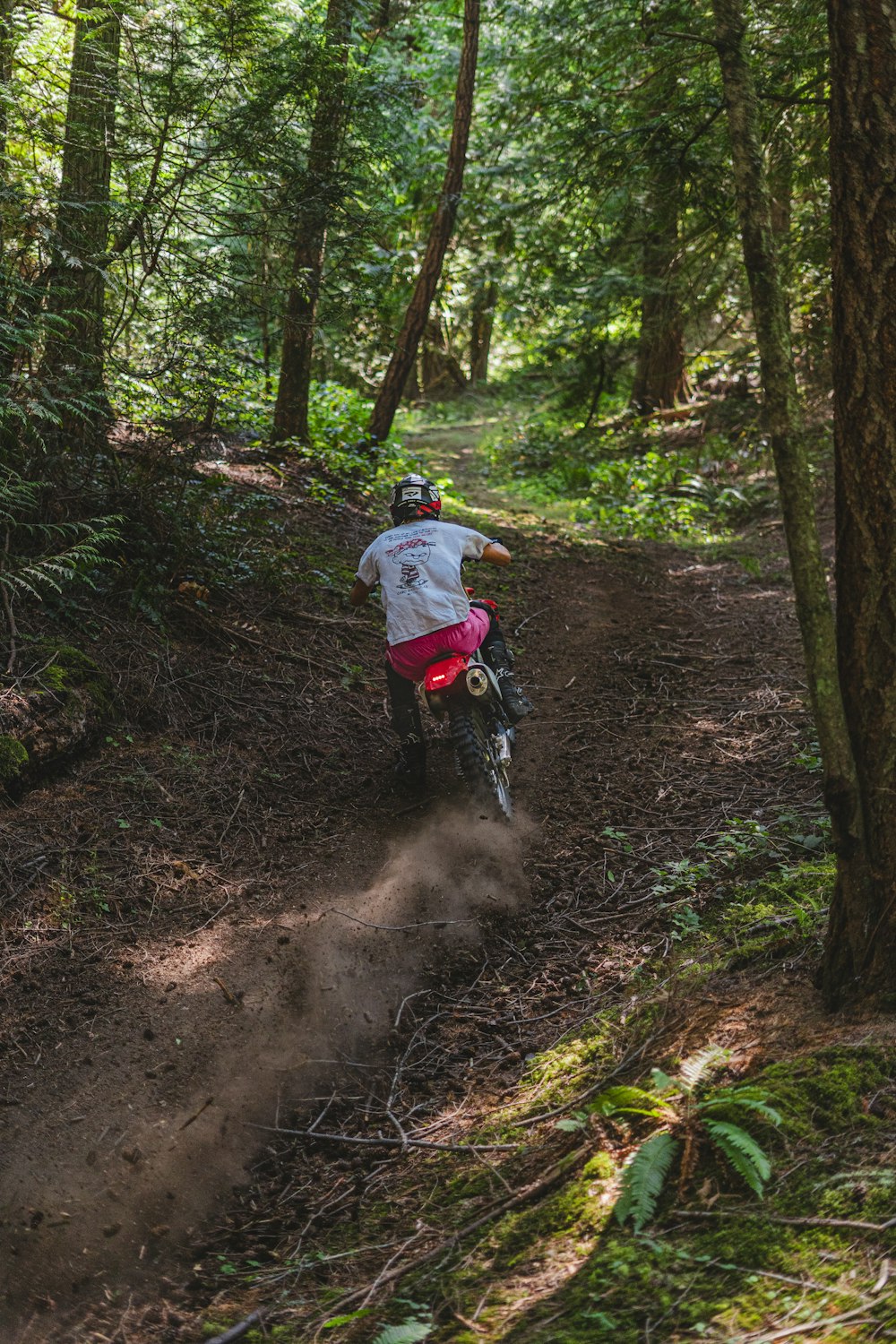 a person riding a dirt bike on a trail in the woods