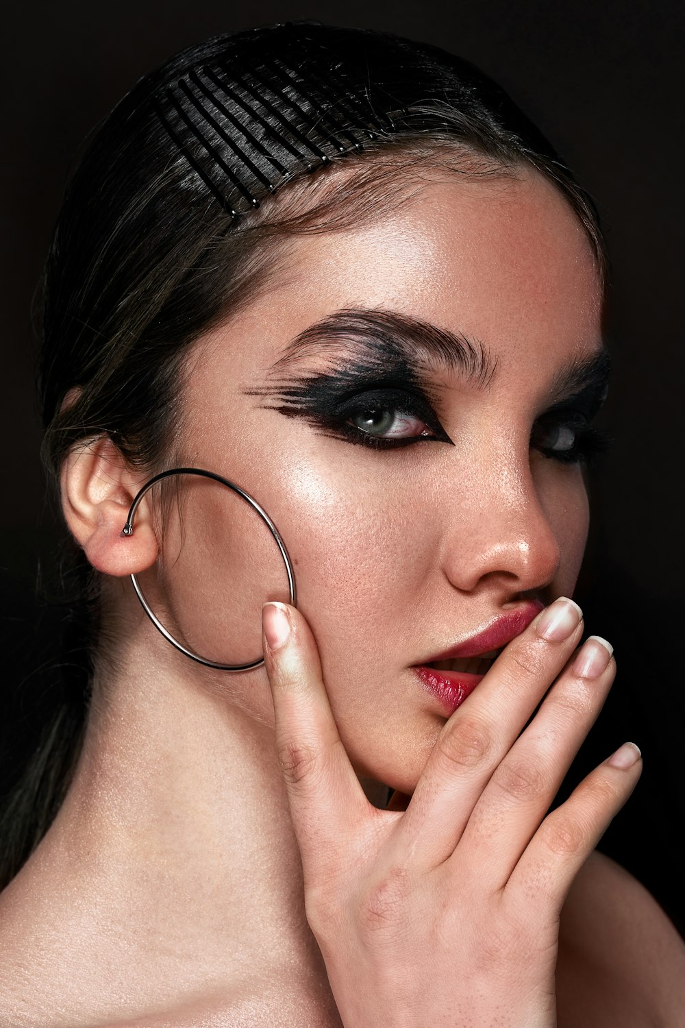 a woman with black makeup and hoop earrings