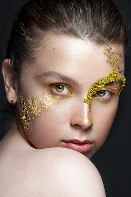 Artistic makeup with shimmering gold highlights and elegant eyeliner for a photoshoot.