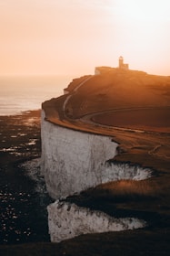 Sunset casting golden light over a coastal road hugging rugged cliffs.