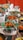 A vibrant display of various dishes served on banana leaves, arranged in metal trays and clay pots. The food includes fried and spicy items, with an assortment of accompaniments around. The setting appears to be a buffet or a festive food setup.