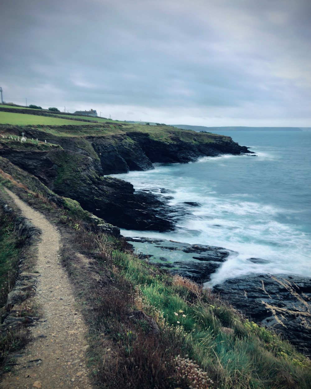 a path leading to the ocean on a cloudy day