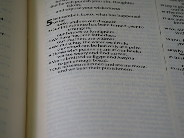 A close-up of a printed page from a book, possibly a religious text, with highlighted verse numbers and sentences. The text discusses themes of loss, exile, and ancestral guilt.