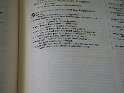 A close-up of a printed page from a book, possibly a religious text, with highlighted verse numbers and sentences. The text discusses themes of loss, exile, and ancestral guilt.